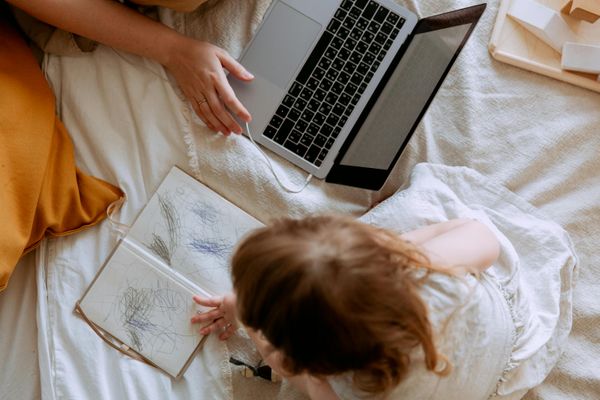Mom working from her bed next to a toddler
